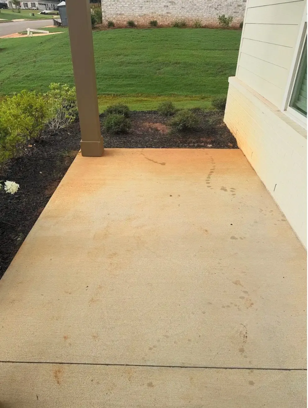 Before cleaning. Concrete apron beside a home discolored by red clay, then cleaned