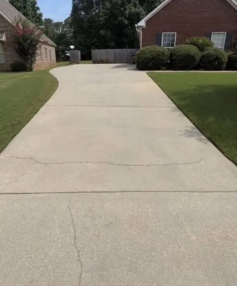 After cleaning by East Alabama Surface Clean. Long concrete driveway with a dark center lane, then cleaned